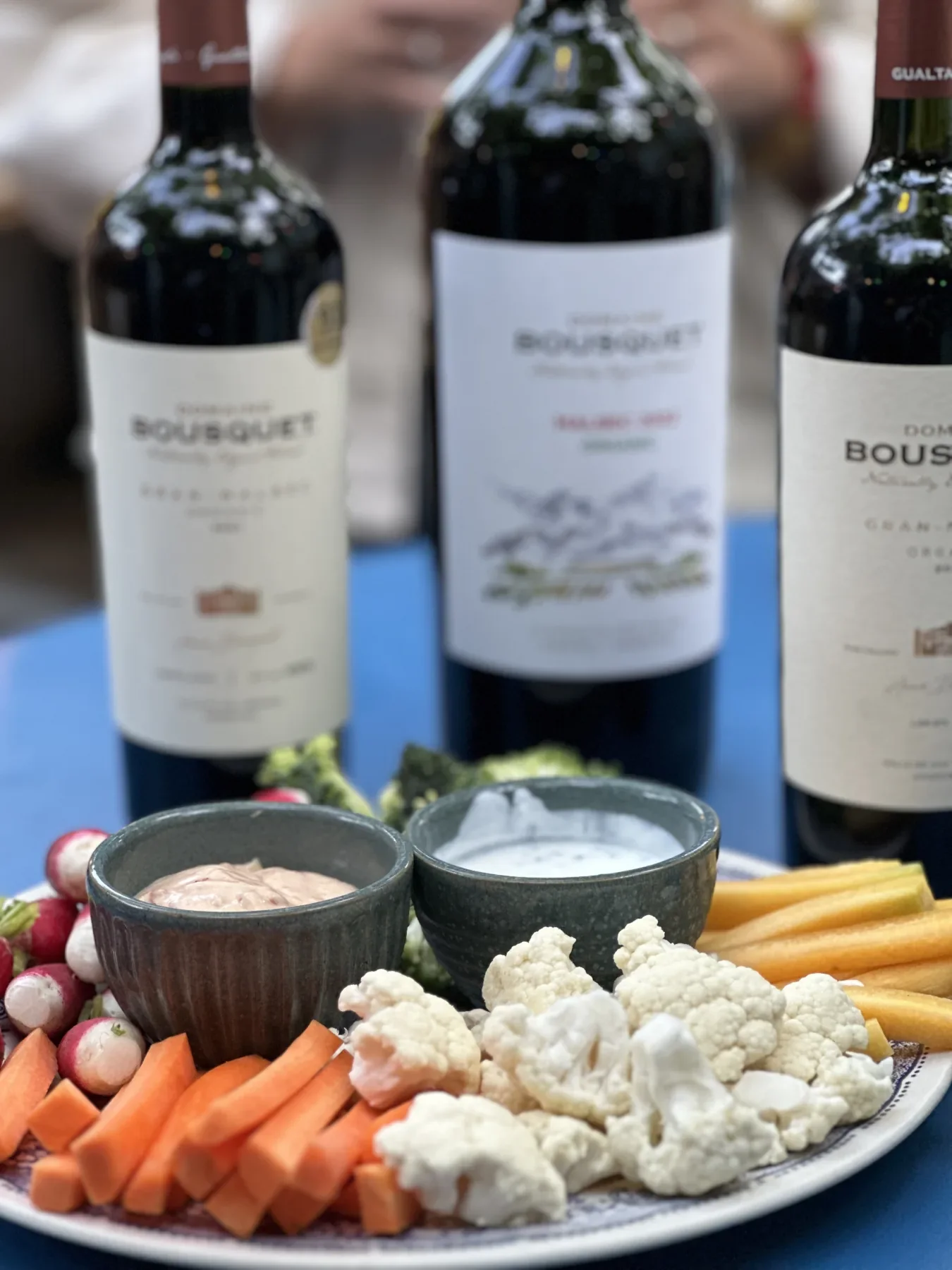 Crudités et sauces maison, bouteilles de bordeaux en arrière-plan