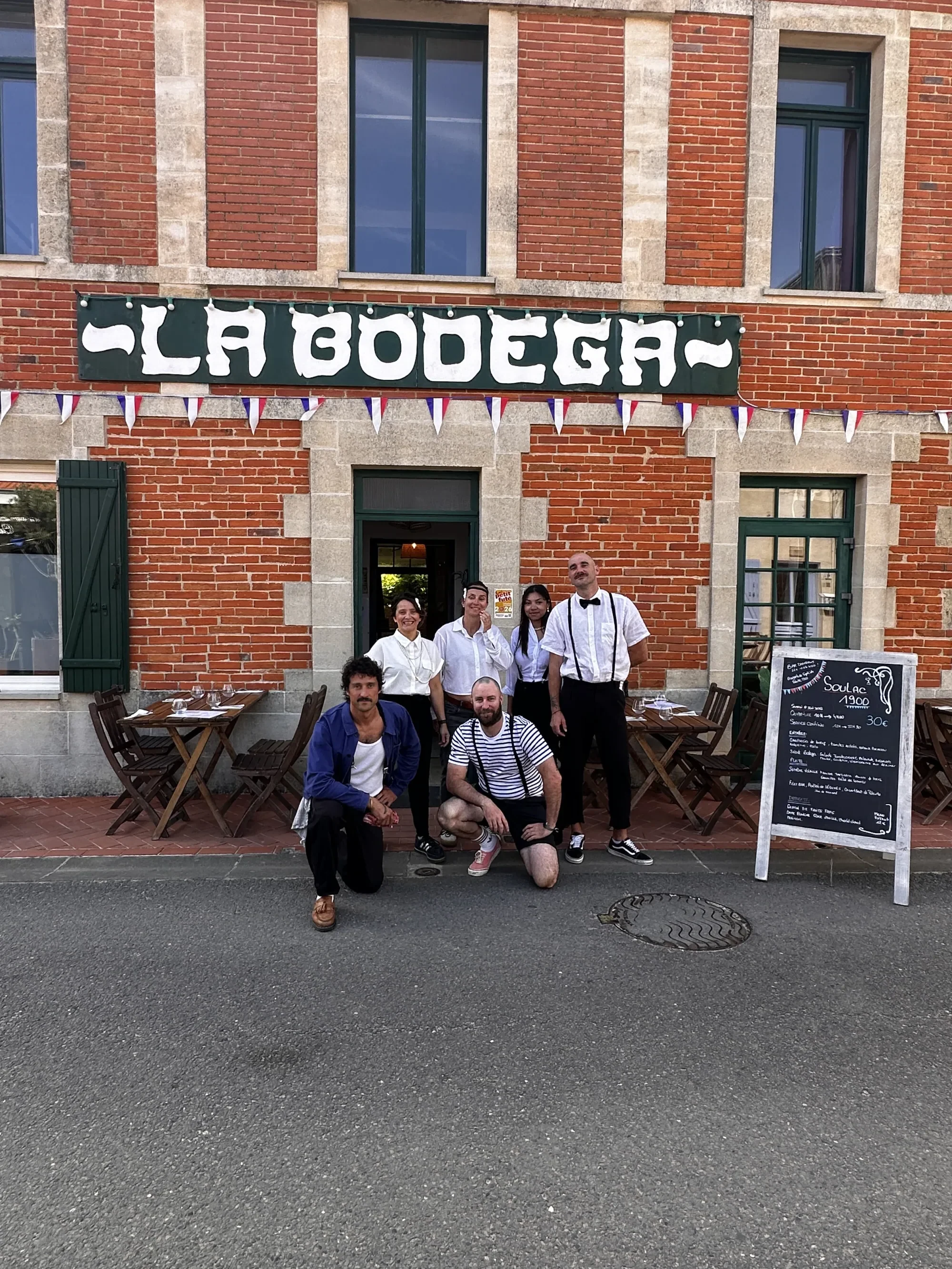 L'équipe de La Bodega devant la façade, sous les fanions tricolores