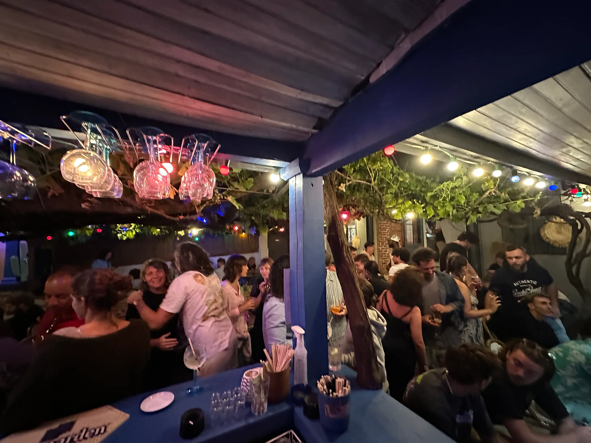 L'intérieur de La Bodega un samedi soir — salle pleine, lumières chaudes, brique apparente, lampe en paille