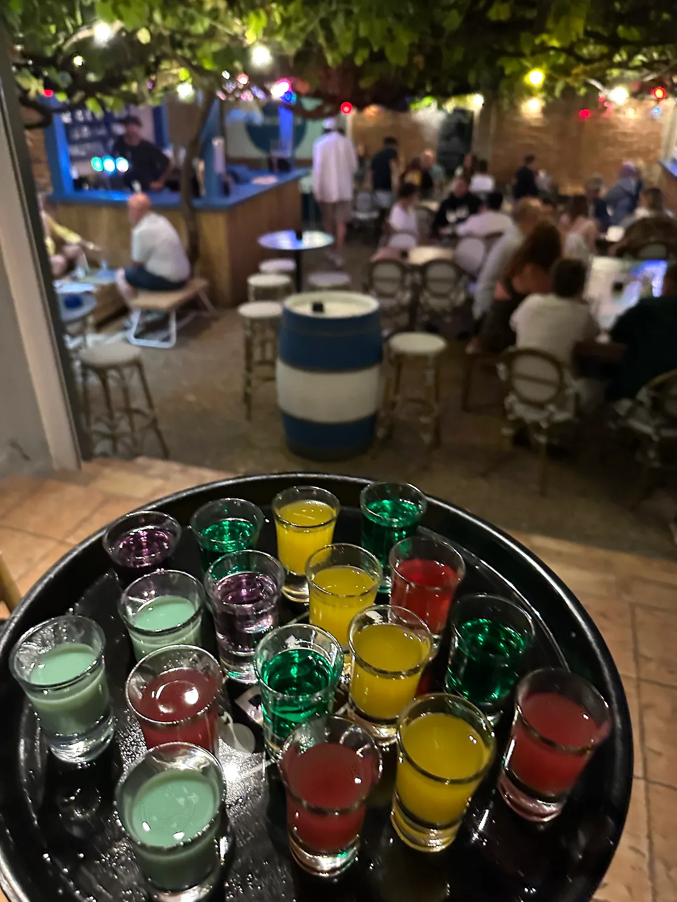 La tonnelle de La Bodega un soir d'été — tables pleines, guirlandes allumées, ambiance bar de nuit